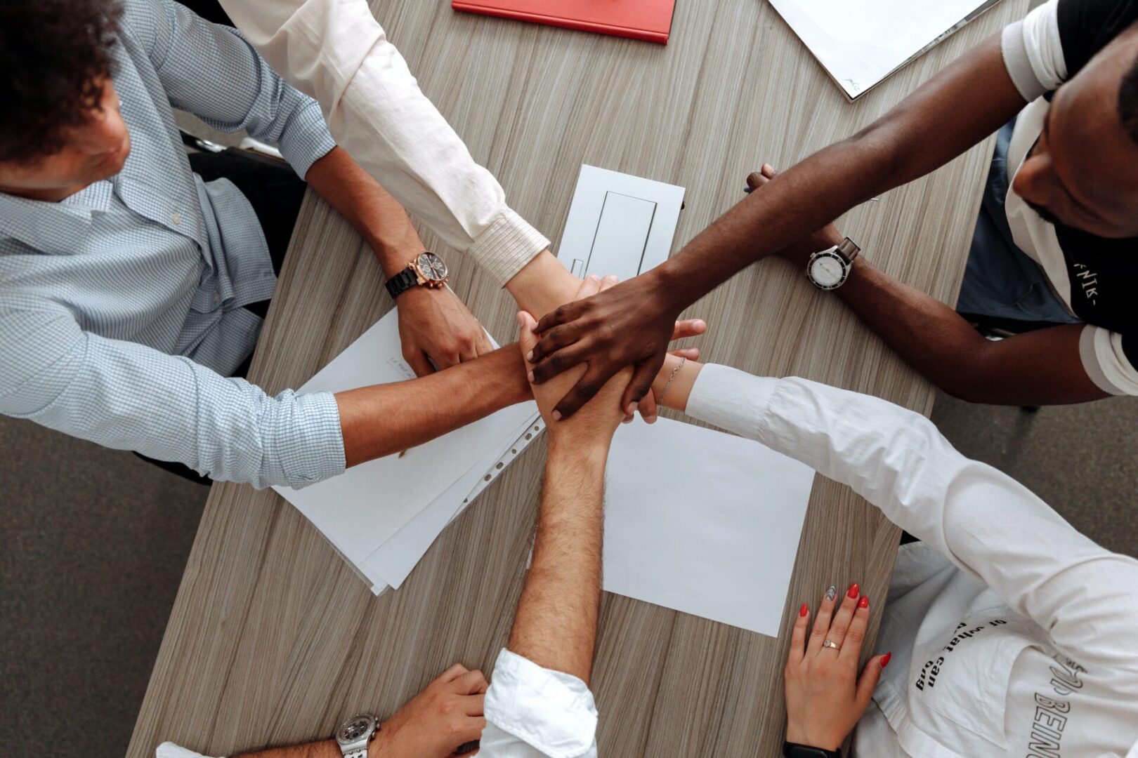 A diverse group of people holding hands in a circle, symbolizing unity and collaboration in a community or team setting