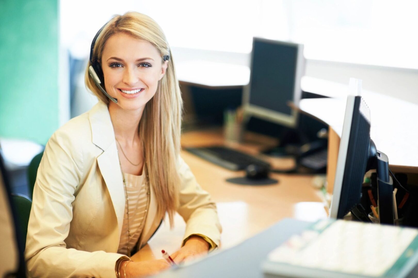 A woman sitting at her desk with headphones on, engaged in a business call or video conference for professional communication.